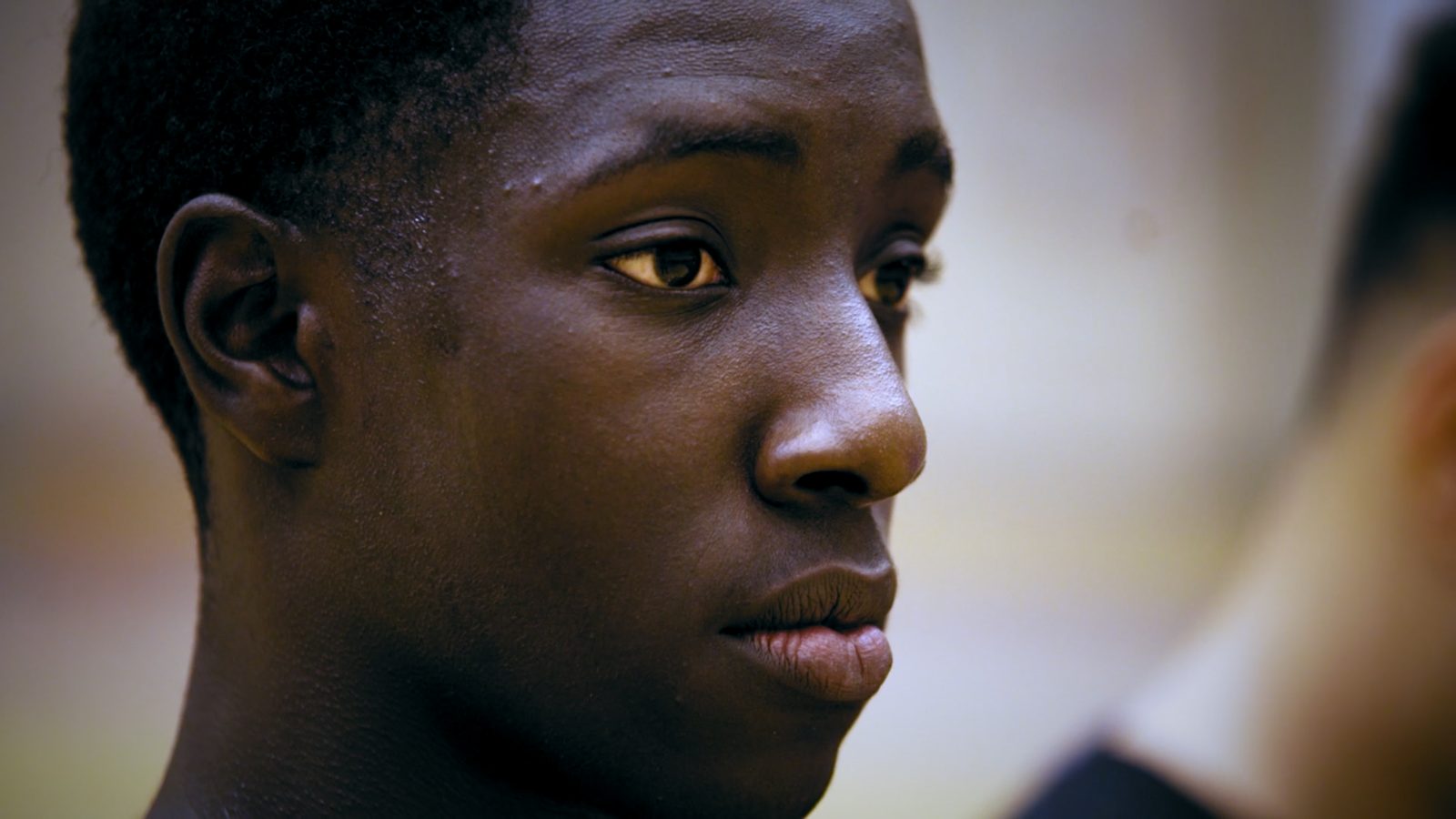 A young athlete in profile, basketball court behind